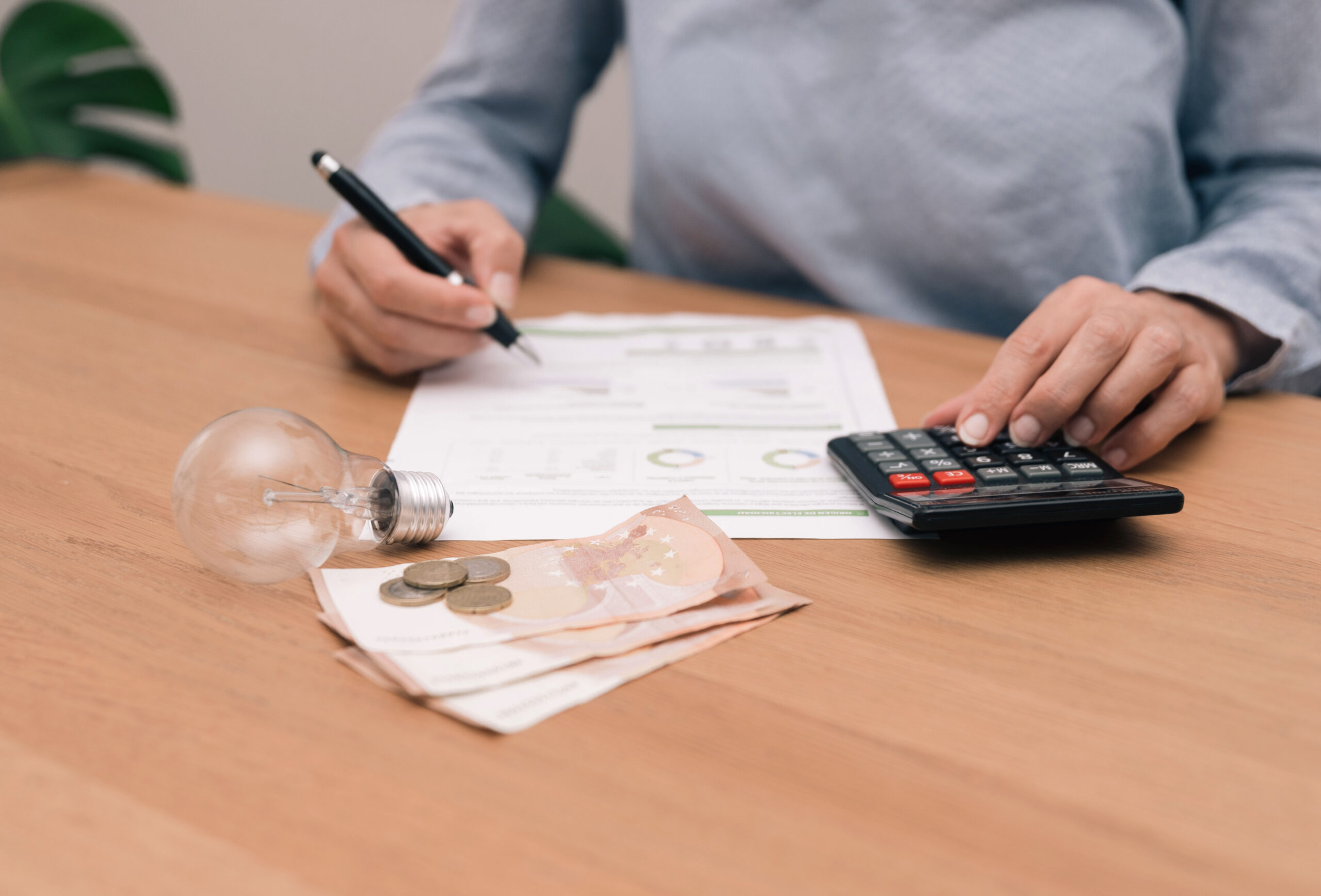 Personne examinant une facture d’électricité avec une calculatrice et une ampoule