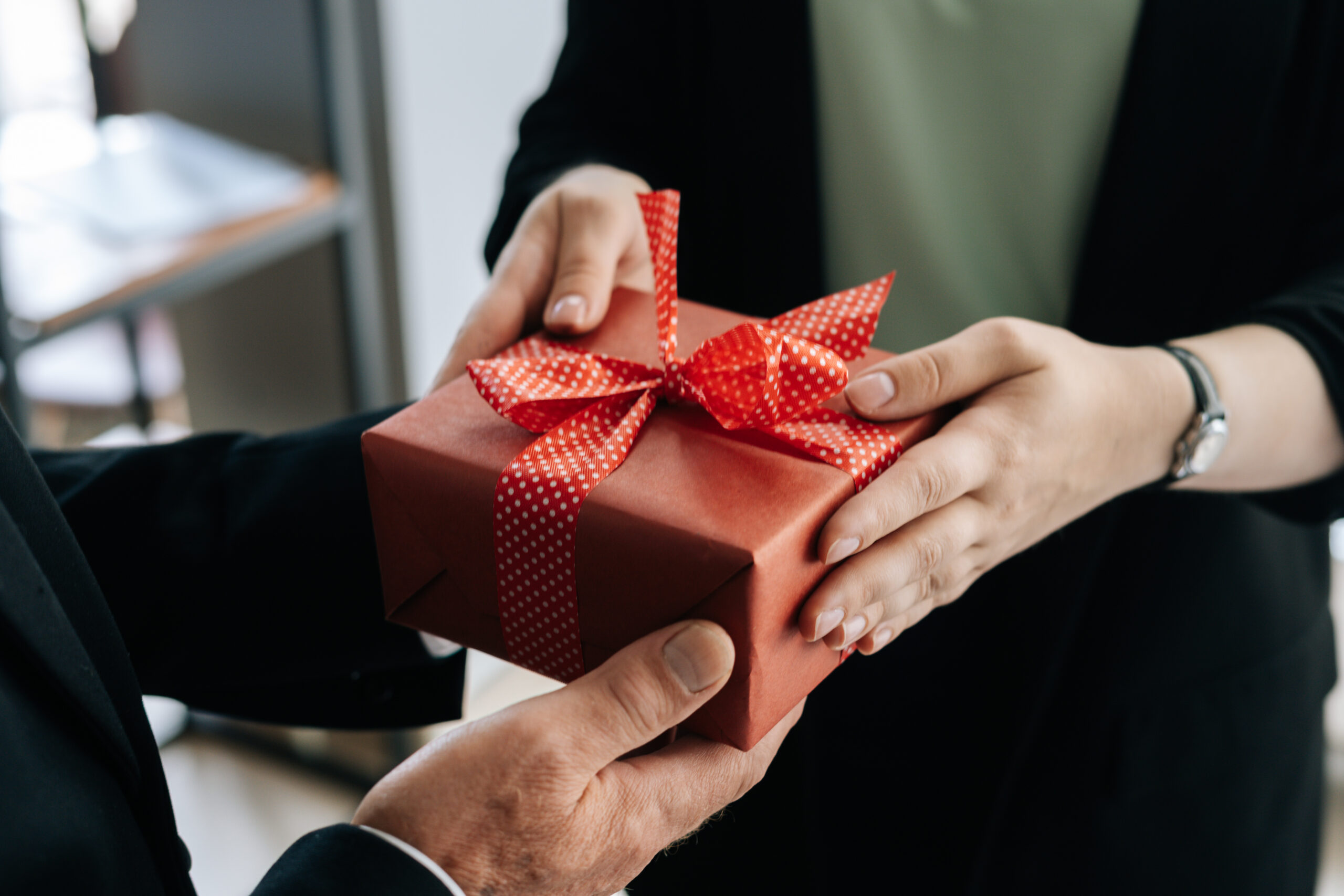 Une femme remet un cadeau rouge à un homme
