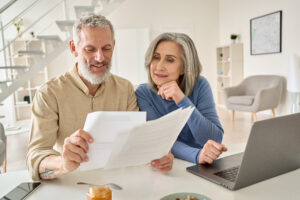 Un couple consulte des documents et calcule sa pension sur un ordinateur portable