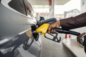 Une main tient un pistolet de carburant dans le réservoir d’une voiture.